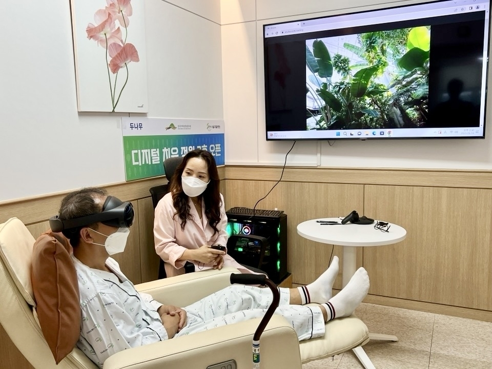 디지털 치유 정원 2호점이 설치된 서울재활병원에 입원 중인 환자가 국립세종수목원을 촬영한 VR 영상을 직접 체험하고 있다. [두나무 제공]