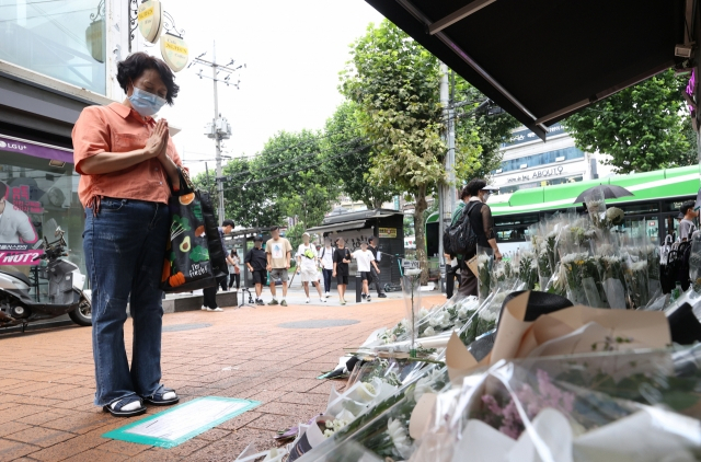 서울 관악구 신림역 인근 상가 골목에 마련된 흉기난동 사건으로 숨진 20대 남성 피해자 A씨를 위한 추모 공간에서 한 시민이 기도하고 있다. [연합]