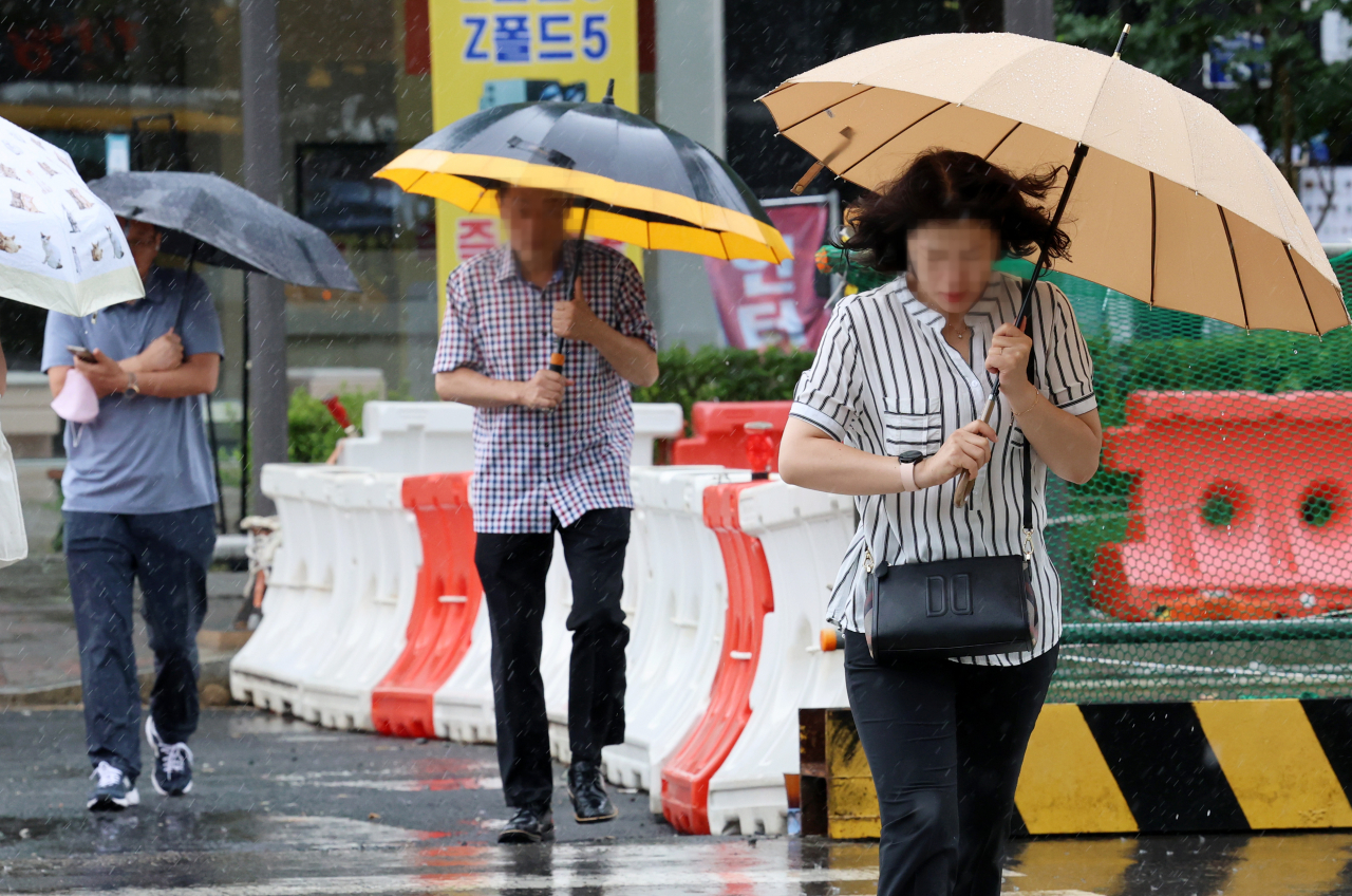 태풍 카눈이 한반도에 진입한 10일 오전 광주 서구 치평동에서 출근길에 나선 시민들이 내리는 비바람에 발걸음을 재촉하고 있다.[연합]
