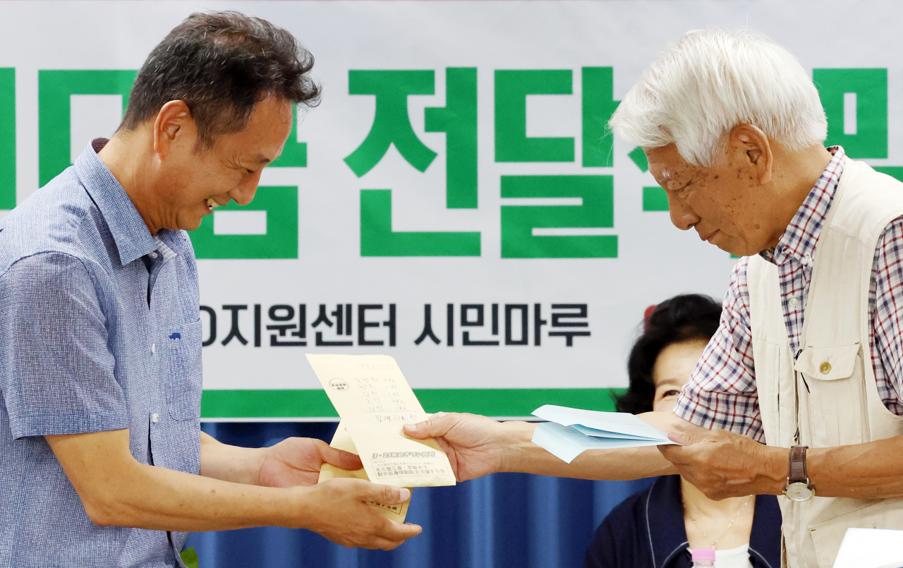 14일 오후 광주 동구 전일빌딩245 4층 시민마루에서 열린 한일역사정의평화행동·광주전남역사지킴이의 시민모금 전달식에서 이국언 일제강제동원시민모임 이사장이 일본 시민단체 '나고야 미쓰비시 조선여자근로정신대 소송을 지원하는 모임' 다카하시 마코토 대표로부터 성금을 전달받고 있다.[연합]