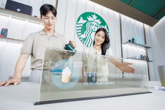 LG디스플레이 모델이 스타벅스와 협업한 매장용 투명 OLED 콘셉트를 소개하고 있다. [LG디스플레이 제공]