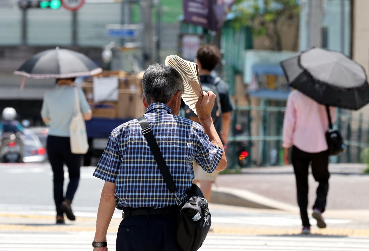 지난달 31일 부산진구 부산시민공원 앞 횡단보도를 시민이 부채를 들고 햇볕을 가리고 있다(사진은 기사 내용과 관련 없음). [연합]