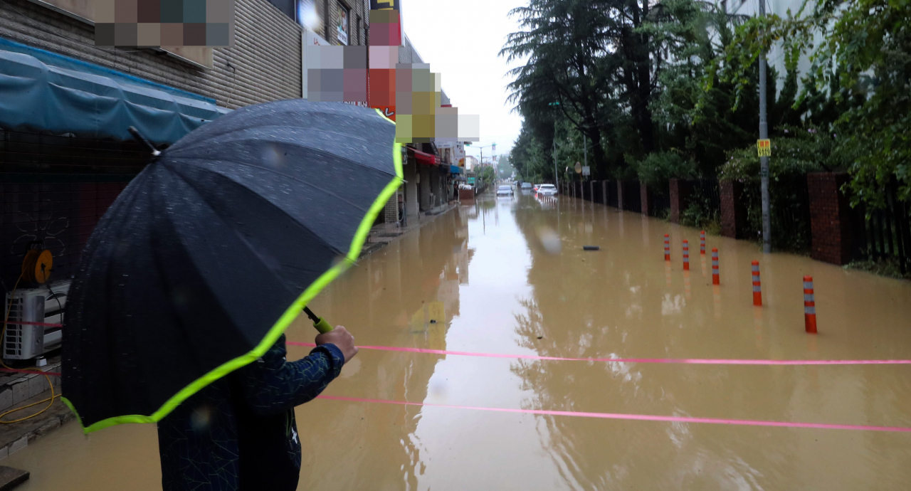 A resident looks at a road in Seongsan-gu, Changwon, South Gyeongsang Province, as a typhoon unusually dropped heavy rain on Aug. 10. (Yonhap)