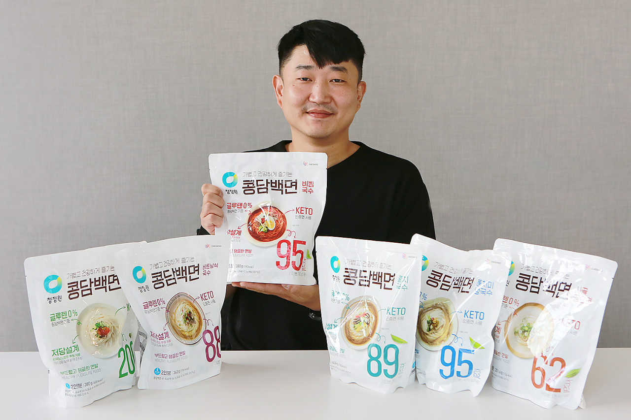 김용건 대상 청정원 식품연구소 수석연구원이 본인이 개발한 콩담백면 제품들과 함께 환하게 미소짓고 있다. 김 연구원이 가장 좋아하는 제품 중 그 중에서도 ‘비빔국수 토토사이트 행오버이라고 한다. [대상 제공]