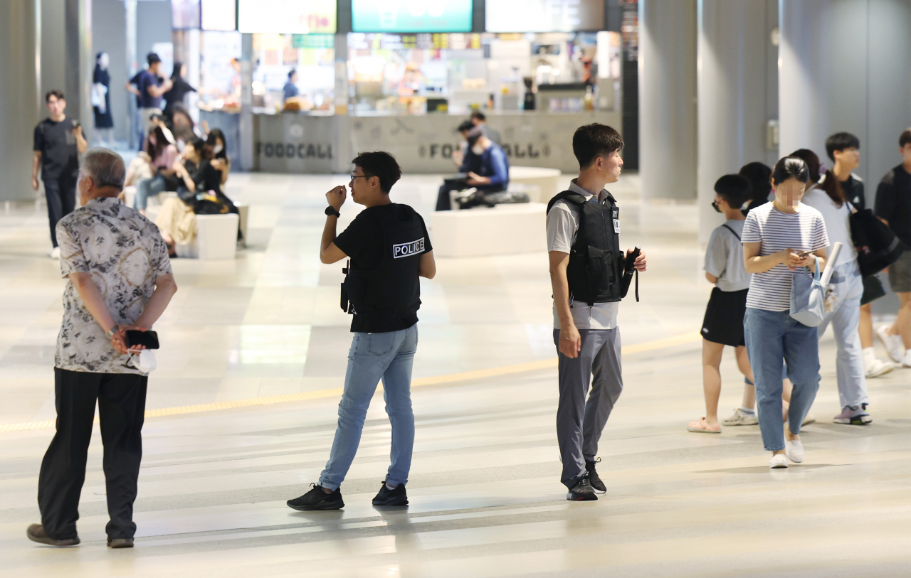 Police officers patrol the underground alleys of Jamsil subway station in August as a post threatening to murder random people spread online. (Yonhap)