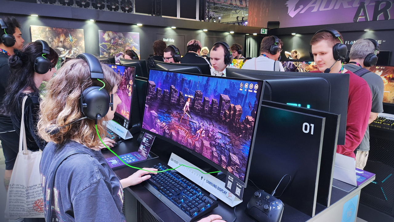 Visitors play Hybe IM's new online game, "Dragon Blaze 2: Knights of Veda," on QD-OLED gaming monitors at the Gamescom 2023 in Cologne, Germany, Wednesday. (Samsung Display)