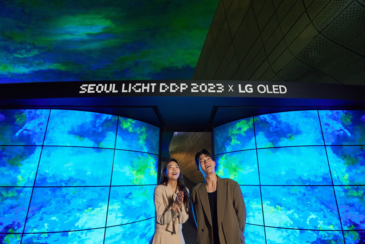 LG전자가 이달 10일까지 서울 동대문디자인플라자에서 열리는 ‘서울라이트 DDP 2023’에서 세계적인 설치미술가 댄 아셔와 협업해 올레드 디스플레이로 아름다운 오로라의 감동을 선사한다. 모델들이 대형 올레드 조형물과 밤하늘에 펼쳐진 오로라를 감상하고 있다. [LG전자 제공]