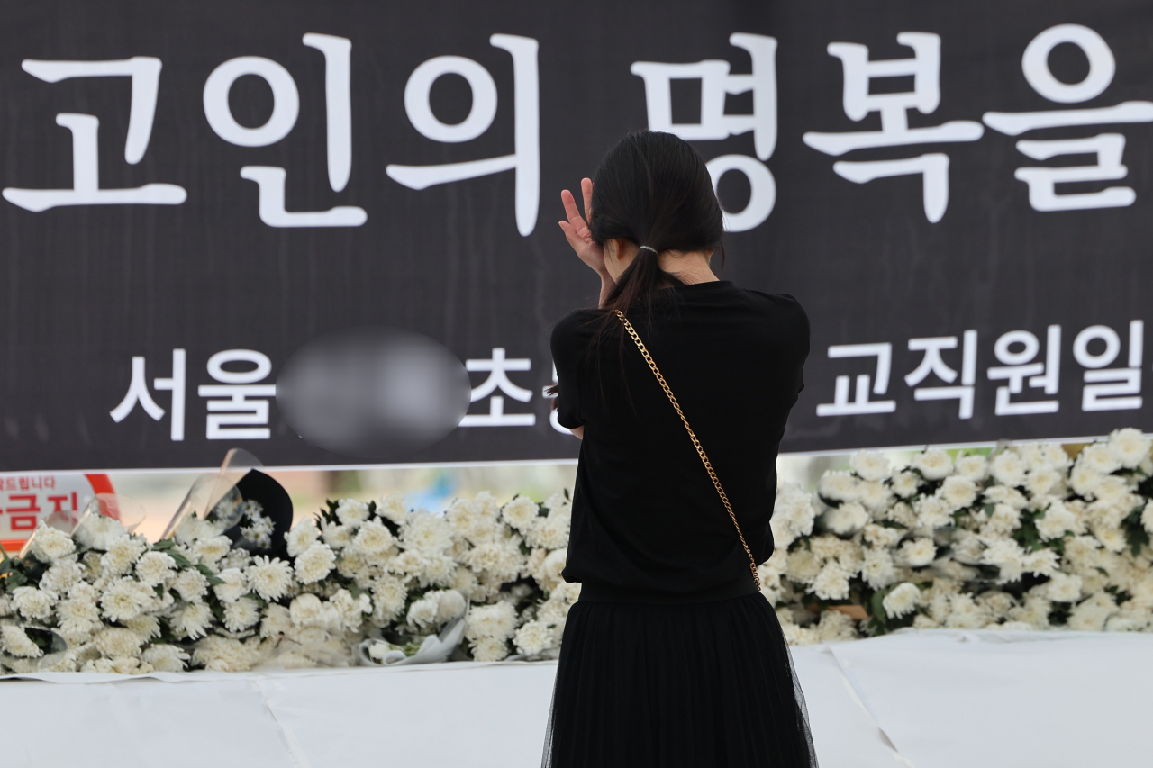 3일 서울 양천구의 한 초등학교 정문에 마련된 교사 A씨 추모공간을 방문한 시민이 눈물을 흘리고 있다. 14년 차 초등교사인 A씨는 지난달 31일 오후 7시께 경기 고양시 덕양구의 한 아파트에서 추락해 숨졌다. [연합]