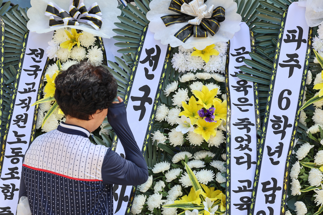 지난 2일 서울 양천구 소재 초등학교 앞에 마련된 숨진 교사 A씨의 추모공간에서 한 추모객이 눈물을 닦고 있다. [연합]