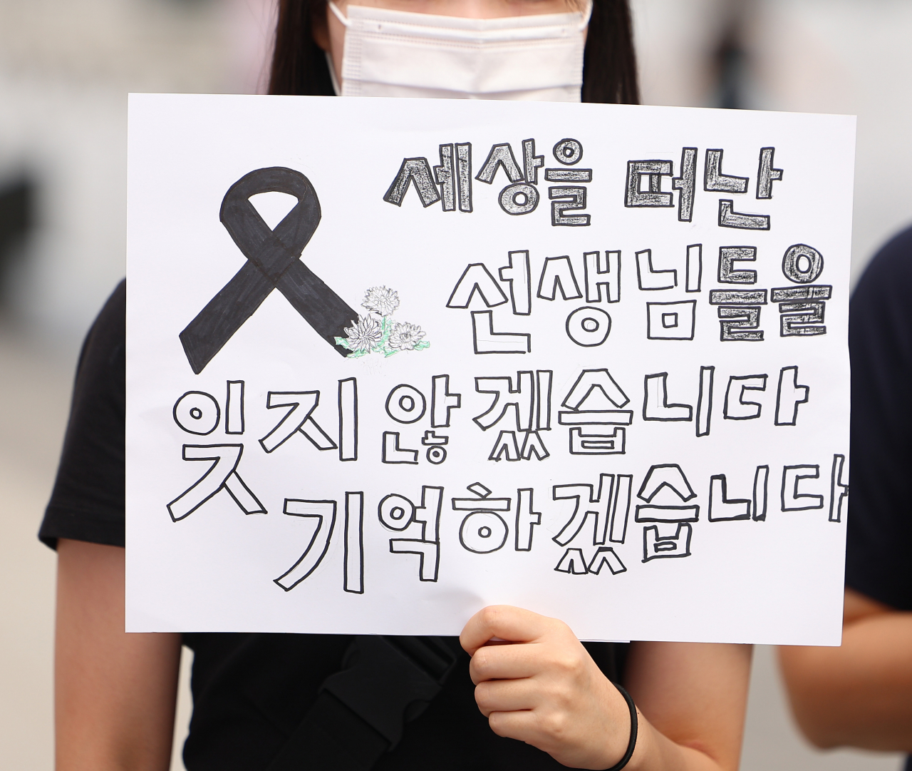 서울 서초구 초등학교에서 숨진 교사의 49재이자 이를 추모하는 '공교육 멈춤의 날'인 4일 서울 광화문광장 이순신 장군 동상 앞에서 열린 '공교육 멈춤의 날' 지지 기자회견에서 참가 학생이 피켓을 들고 있다. [연합]