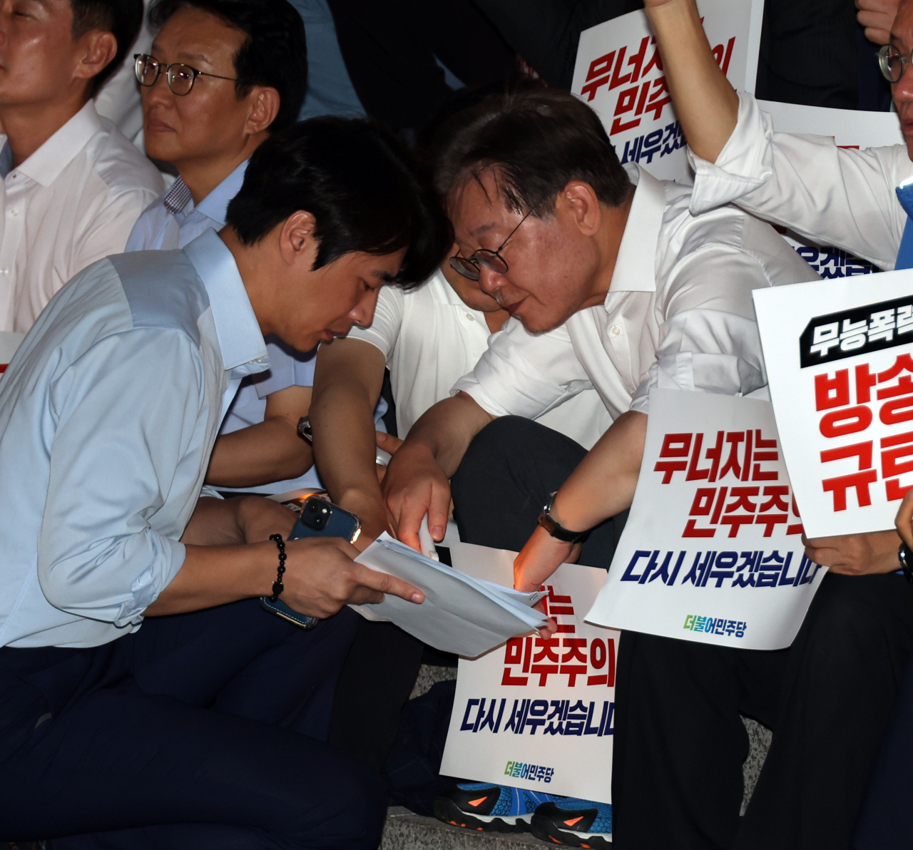 이재명 더불어민주당 대표가 5일 국회 앞 계단에서 열린 민주주의 회복 촛불문화제에서 한준호 의원과 대화하고 있다. [연합]