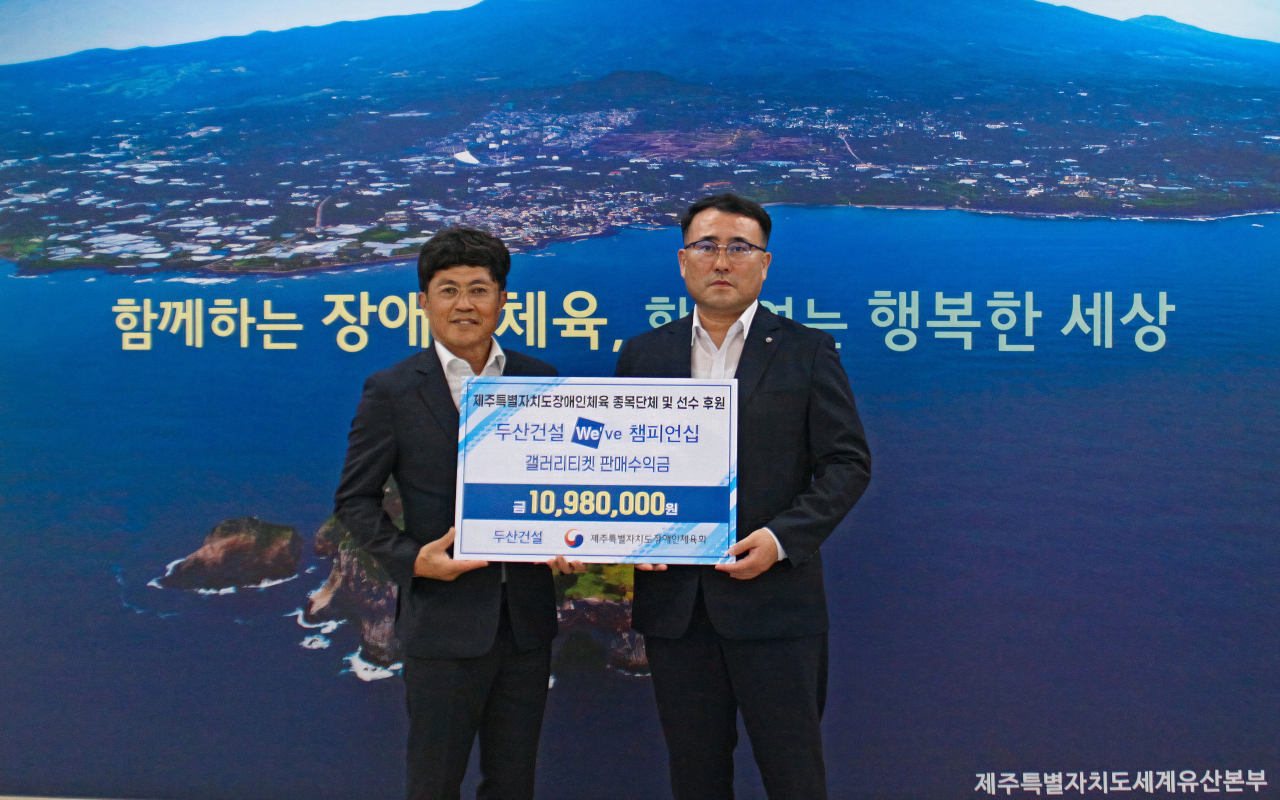 오세욱 두산건설 상무, 정재훈 제주특별자치도 장애인체육회 상임부회장(왼쪽부터)이 기부금 전달식에서 사진 촬영을 하고 있다[사진=두산건설]
