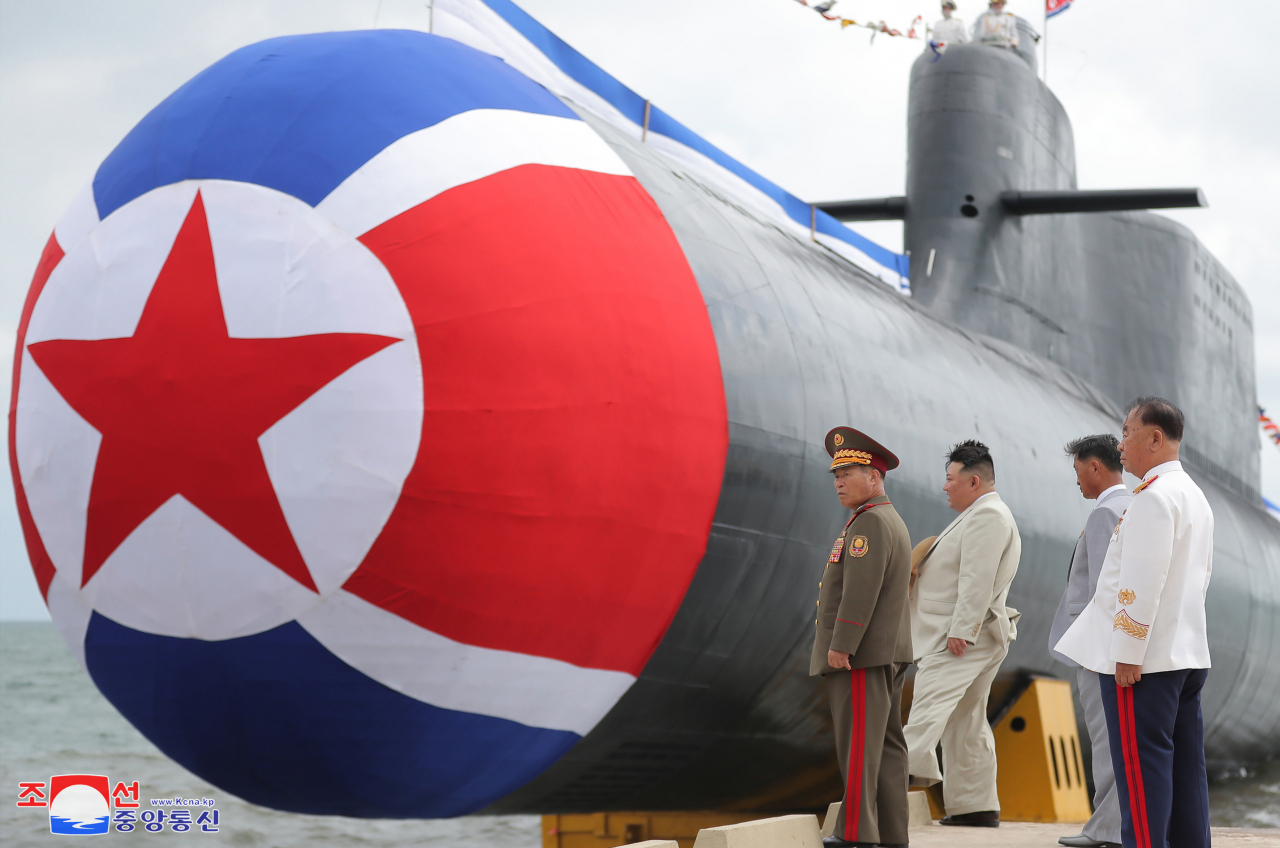This photo, provided by North Korea's official Korean Central News Agency on Friday, shows North Korean leader Kim Jong-un (second from left) attending a ceremony on Wednesday to launch a newly built "tactical nuclear attack submarine." (Yonhap)