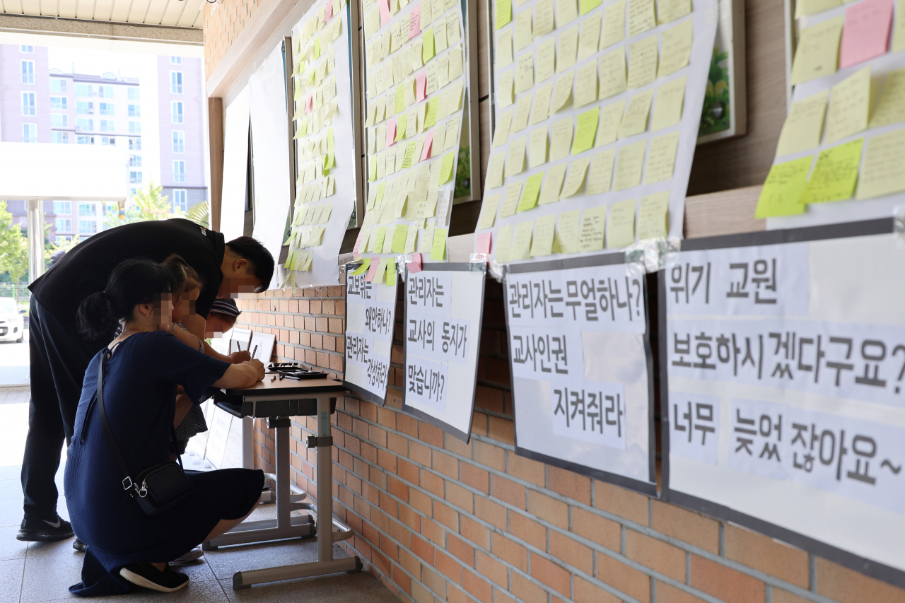 악성민원으로 세상을 뜬 대전 초등 교사가 재직하던 유성구 한 초등학교에 마련된 추모공간에 9일 오후 한 학부모가 고인을 추모하는 쪽지를 작성하고 있다. 연합뉴스