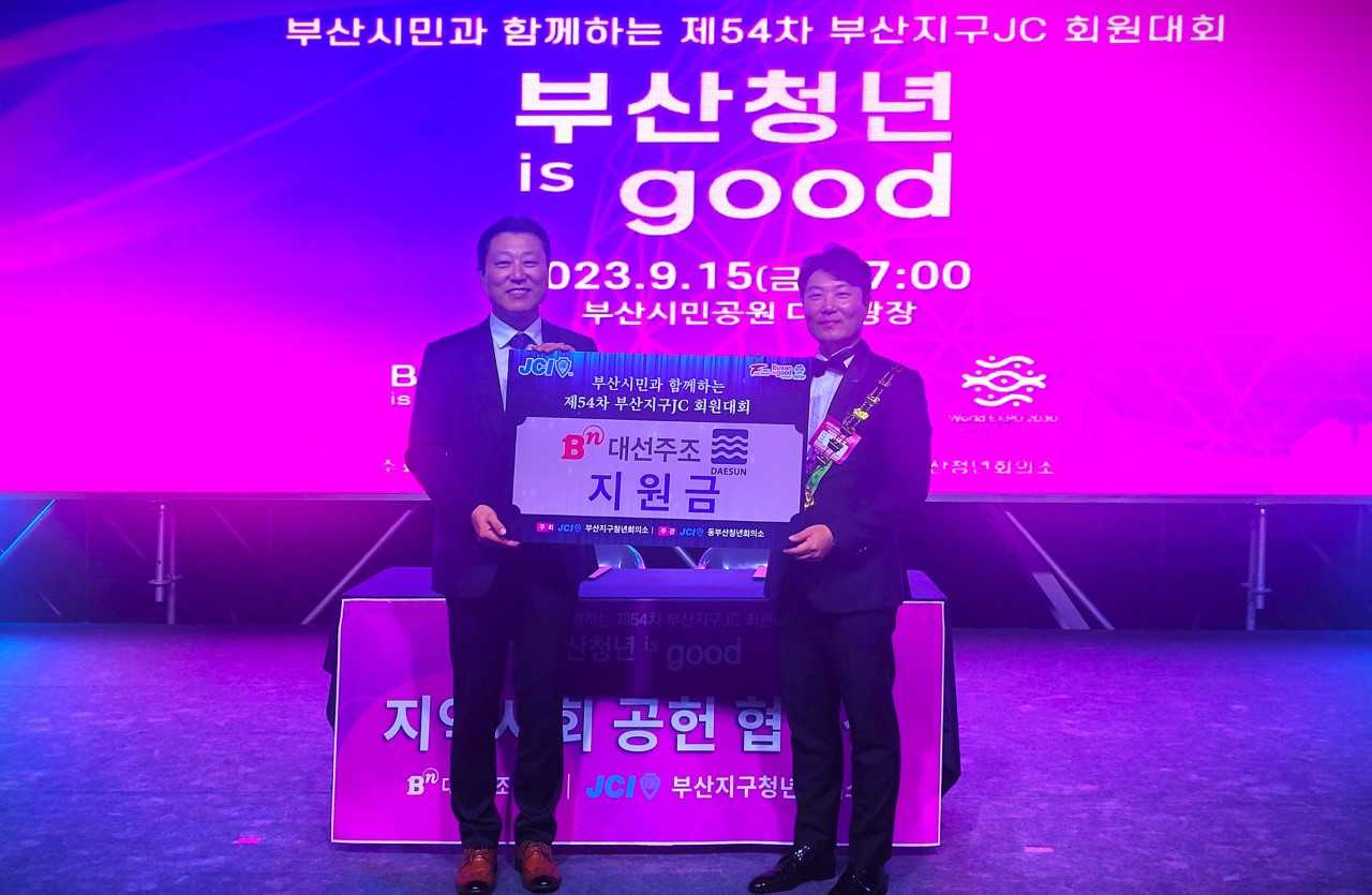 지난 15일 부산시민공원 다솜광장에서 개최된 ‘제54차 부산지구청년회의소 회원대회’에서 (왼쪽부터) 대선주조 최성욱 영업본부장이 부산지구청년회의소 안지환 지구회장에게 사회공헌 후원금을 전달하고 있다. [사진=대선주조]