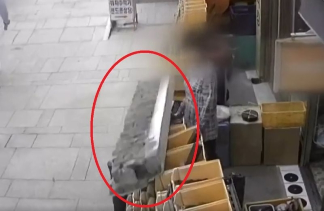 지난 19일 세운상가에서 상인의 머리 앞으로 사람 몸집만한 콘크리트 덩어리(붉은색 원)가 떨어지고 있다.[JTBC 캡처]
