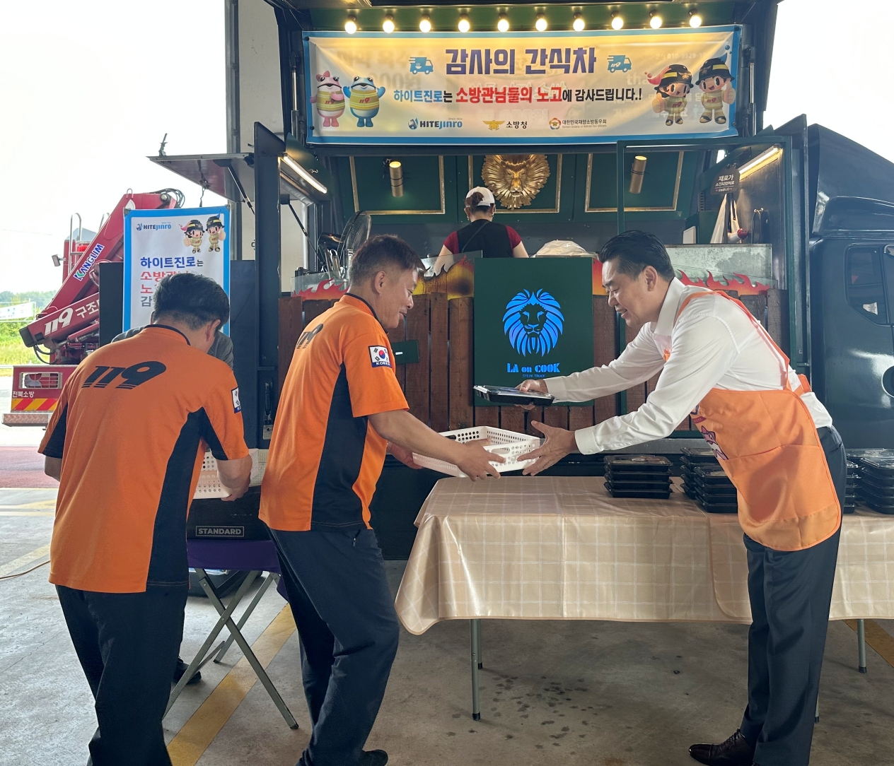 12일 김인규(오른쪽) 하이트진로 대표가 전북 완주소방서 소방공무원에게 간식을 전달하고 있다. [하이트진로 제공]