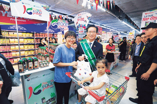 정황근 농림축산식품부 장관이 지난 6월 24일 베트남 하노이 윈마트(Winmart)에서 K-푸드 판매 촉진 행사를 벌이던 도중 현지 소비자와 만나 포즈를 취하고 있다. [농림축산식품부 제공]