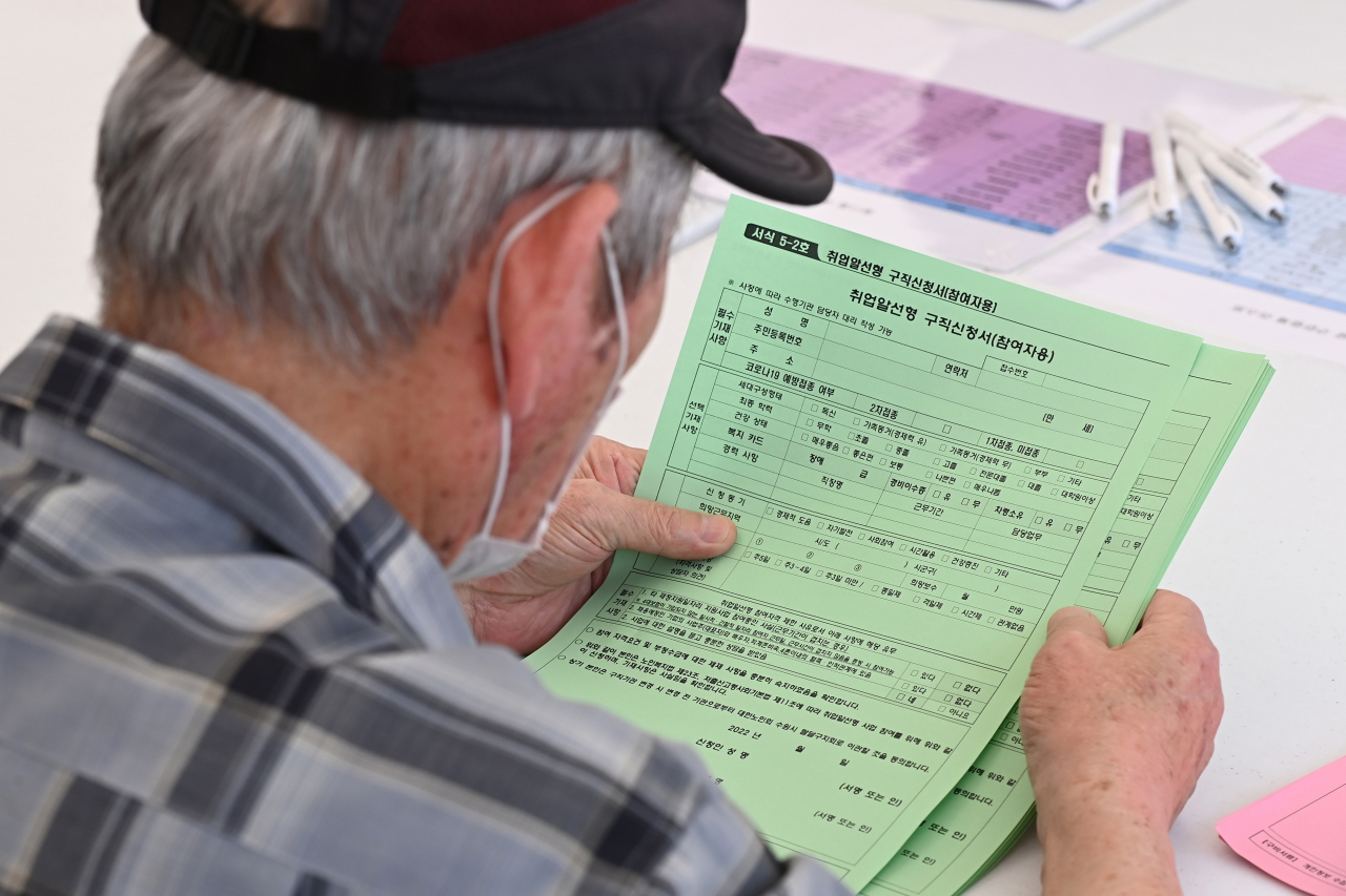 A man looks at a job application form at a job fair in Seoul on June 21, 2022. (Newsis)