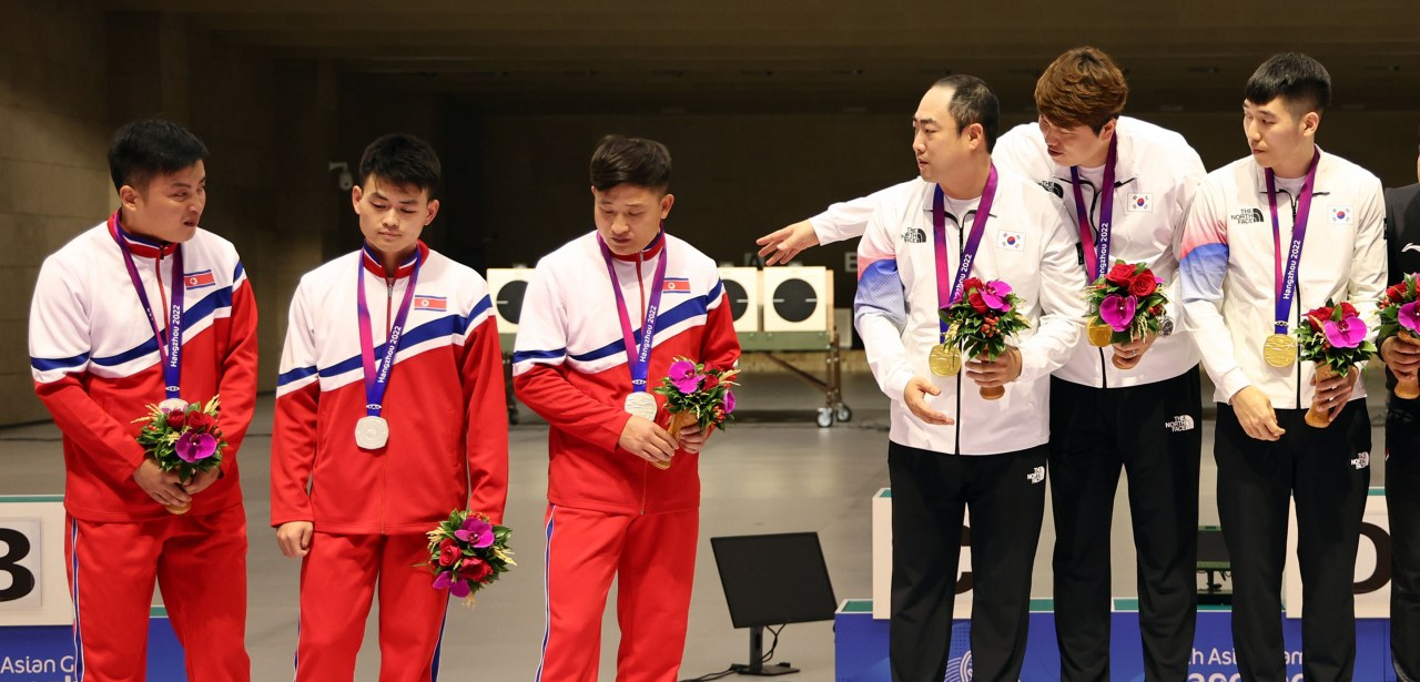25일 중국 항저우 푸양 인후 스포츠센터에서 열린 제19회 항저우 아시안게임 남자 사격 10m 러닝타깃 단체전에서 금메달을 획득한 한국의 정유진과 선수들이 북한 선수들에게 함께 기념촬영할 것을 요청했지만 은메달을 획득한 북한 선수들이 이에 응하지 않고 있다. [연합]