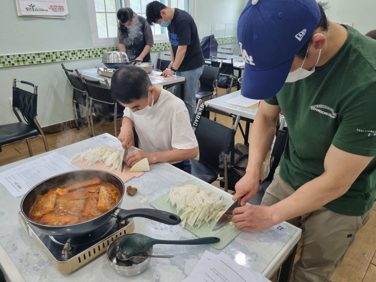 서울 관악구는 중장년 남성 1인 가구 대상의 ‘행복한 밥상’ 프로그램을 운영하며 건강한 식생활과 사회적 관계 형성 등을 돕는다고 27일 밝혔다. 사진은 중장년 1인 가구가 함께 모여 요리하는 장면. [관악구 제공]