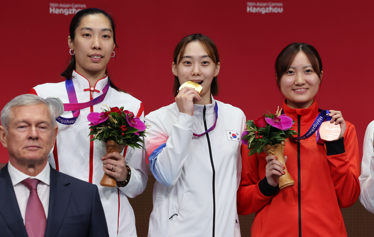 26일 중국 항저우 전자대학 체육관에서 열린 19회 항저우 아시안게임 펜싱 여자 사브르 개인 결승전에서 금메달을 획득한 윤지수가 시상대에 메달을 입에 물고 포즈를 취하고 있다. [연합]