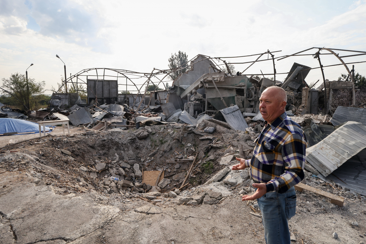 This photo shows a man standing near a shell crater on a farm near the front-line town of Orikhiv, the Zaporizhzhia region of Ukraine, on Sept. 14, 2023. (EPA)