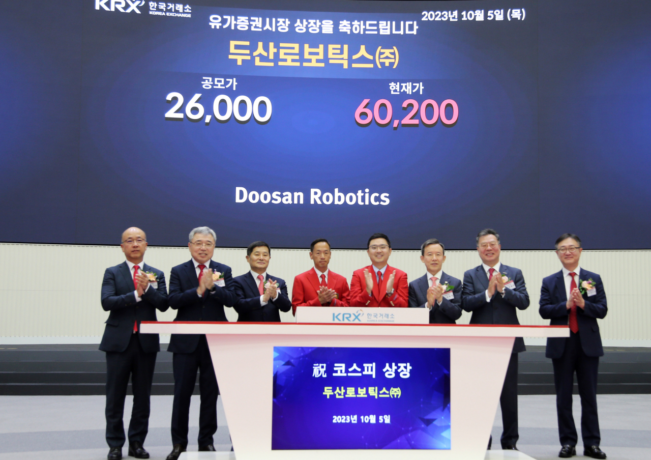 두산로보틱스 박인원(왼쪽 네번째) 대표, 류정훈(왼쪽 다섯번째) 대표가 5일 서울 여의도 한국거래소에서 열린 두산로보틱스 유가증권시장 상장 기념식에서 매매개시 벨을 누른 후 관계자들과 기념촬영을 하고 있다. [두산 제공]