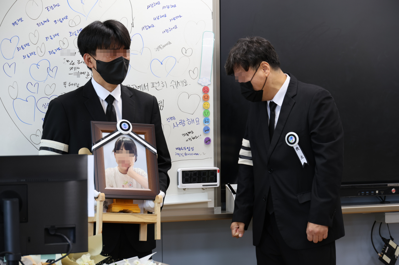 악성민원으로 세상을 뜬 대전 초등 교사의 유족들이 9일 오전, 교사가 재직하던 유성구 한 초등학교 5학년 교실에 영정사진을 들고 들어서며 눈물을 흘리고 있다. [연합]