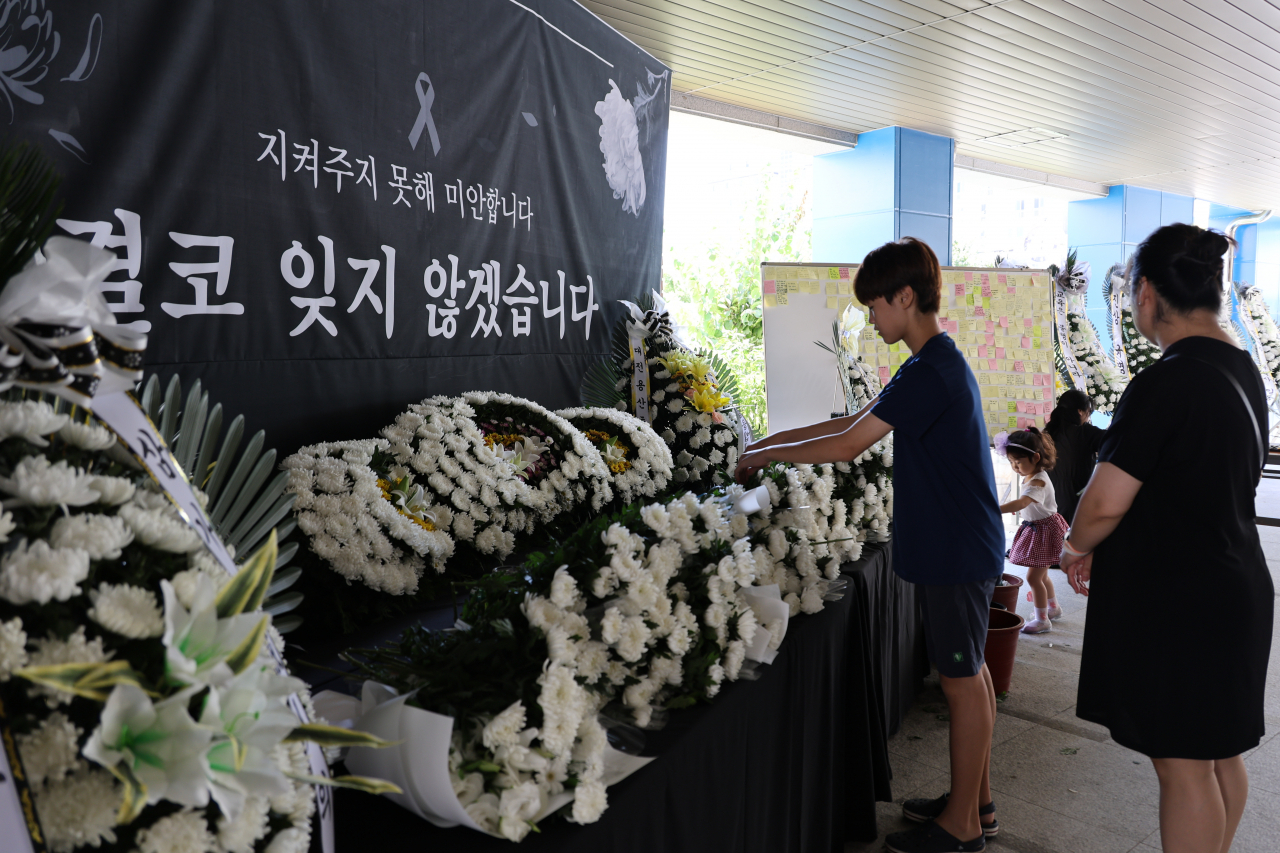 9일 오후 악성민원으로 세상을 뜬 대전 초등 교사가 재직하던 유성구 한 초등학교에 마련된 추모공간을 찾은 학생과 학부모가 고인을 추모하고 있다. [연합]