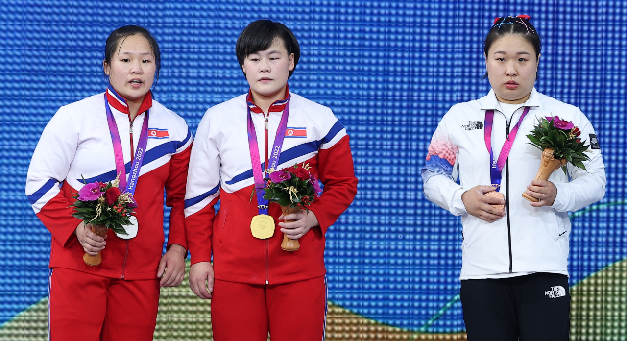5일 중국 항저우 샤오산 스포츠센터에서 열린 2022 항저우 아시안게임 역도 여자 76kg급 그룹 A 경기에서 동메달을 차지한 대한민국 김수현(오른쪽)이 시상식에서 금메달 북한 송국향(가운데), 은메달 북한 정춘휘와 함께 기념촬영을 하기 위해 함께 시상대에 올라 있다. [연합]