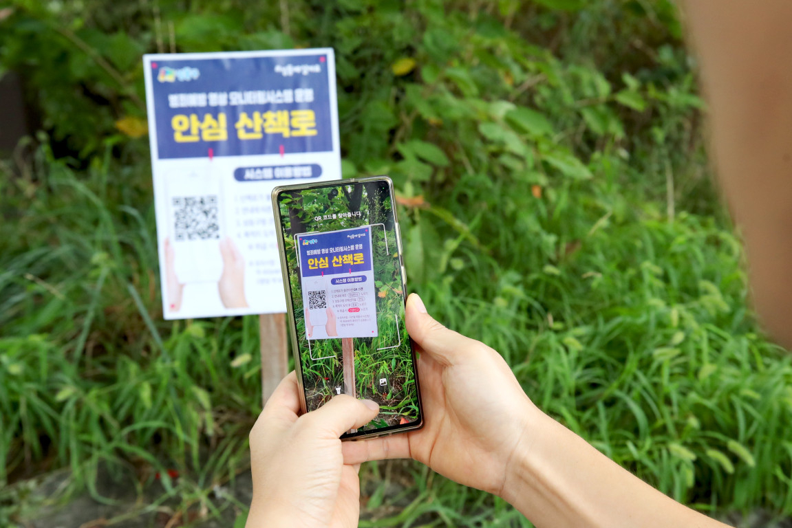 성동구 주민이 구 산책로 범죄예방시스템 QR코드를 찍고 있는 모습. [성동구 제공]