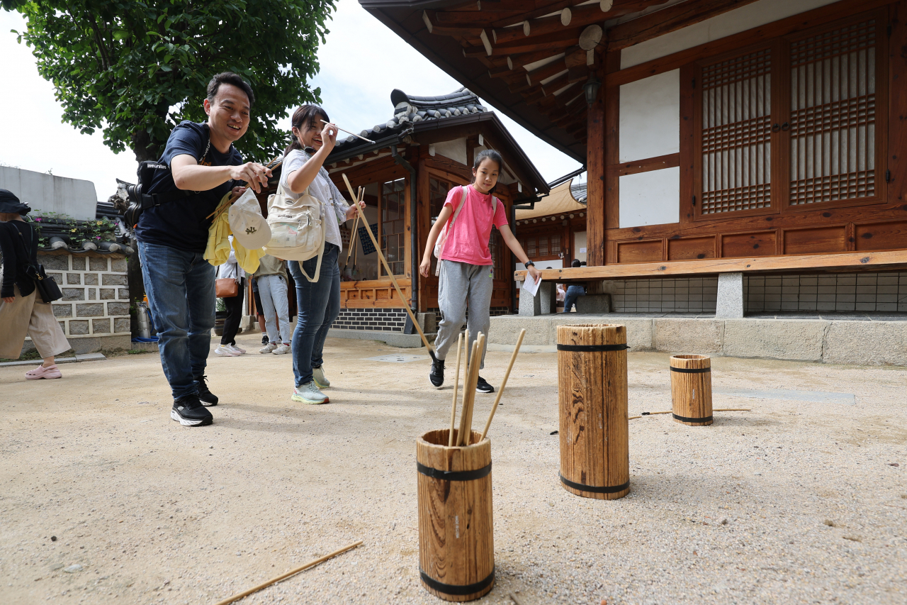 Foreigners play "tuho," a traditional throwing game, during the Chuseok holiday in Bukchon Traditional Culture Center in Seoul, Sept. 29. (Yonhap)