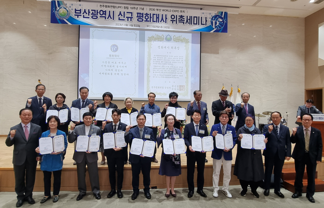 14일 부산가정연합 대강당에서 개최된 천주평화연합 창립 18주년 기념 ‘부산시 신규 평화대사 위촉식’에서 16개 구·군 대표 위촉자 20명이 위촉장을 수여하고 양창식 UPF 세계의장(왼쪽)과 파이팅을 외치고 있다. [사진=임순택 기자]
