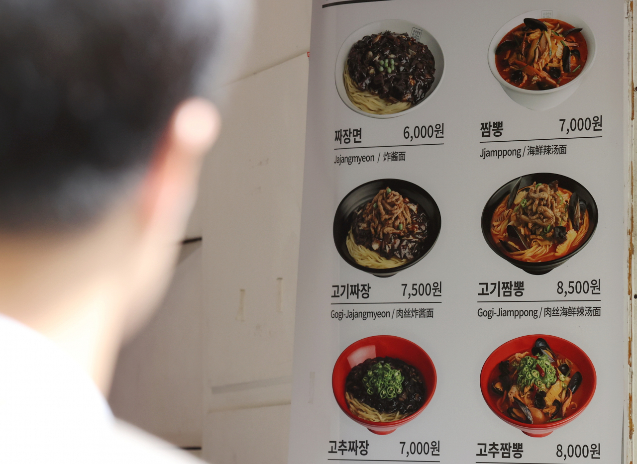 서울 중구 명동의 한 음식점 가격 안내문 앞을 시민이 지나가고 있다.[연합]