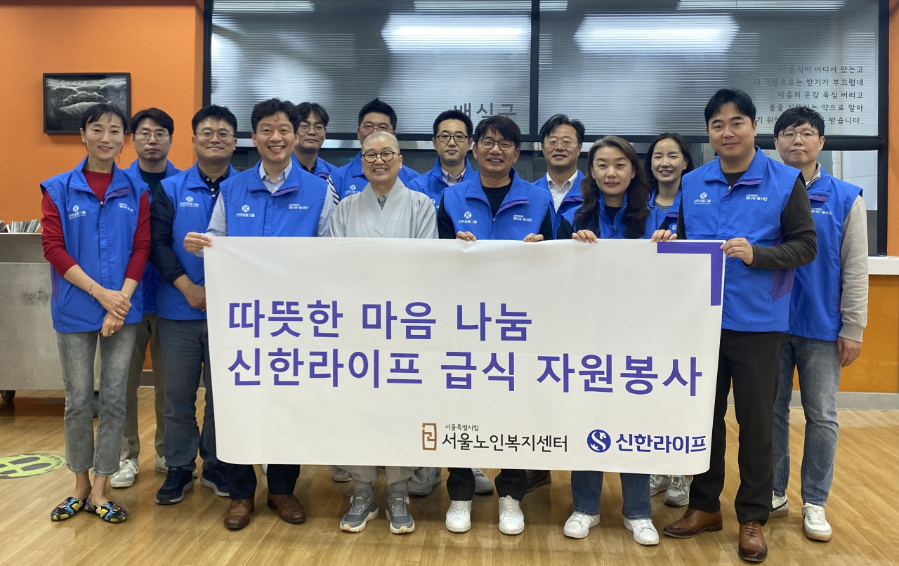 17일 종로구 경운동에 위치한 서울노인복지센터에서 희유 스님(가운데)과 이영종(앞줄 오른쪽 세 번째) 사장 및 임직원들이 배식 봉사활동 전 기념 촬영을 하고 있다. [신한라이프 제공]