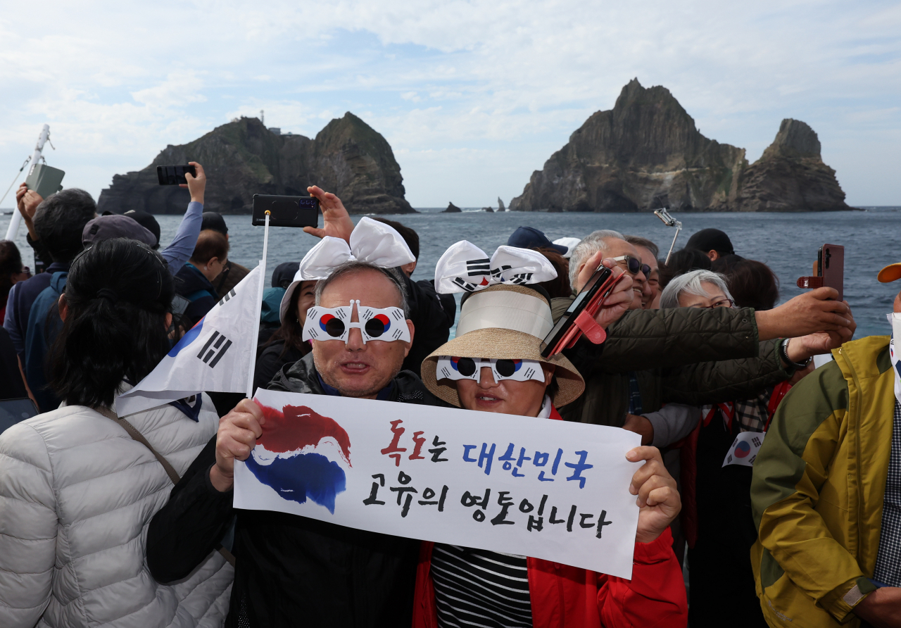 People pose for photos with a banner that reads "Dokdo is the Republic of Korea's territory," after their boat failed to reach the islets due to rough waters and strong winds on Oct. 19. (Yonhap)