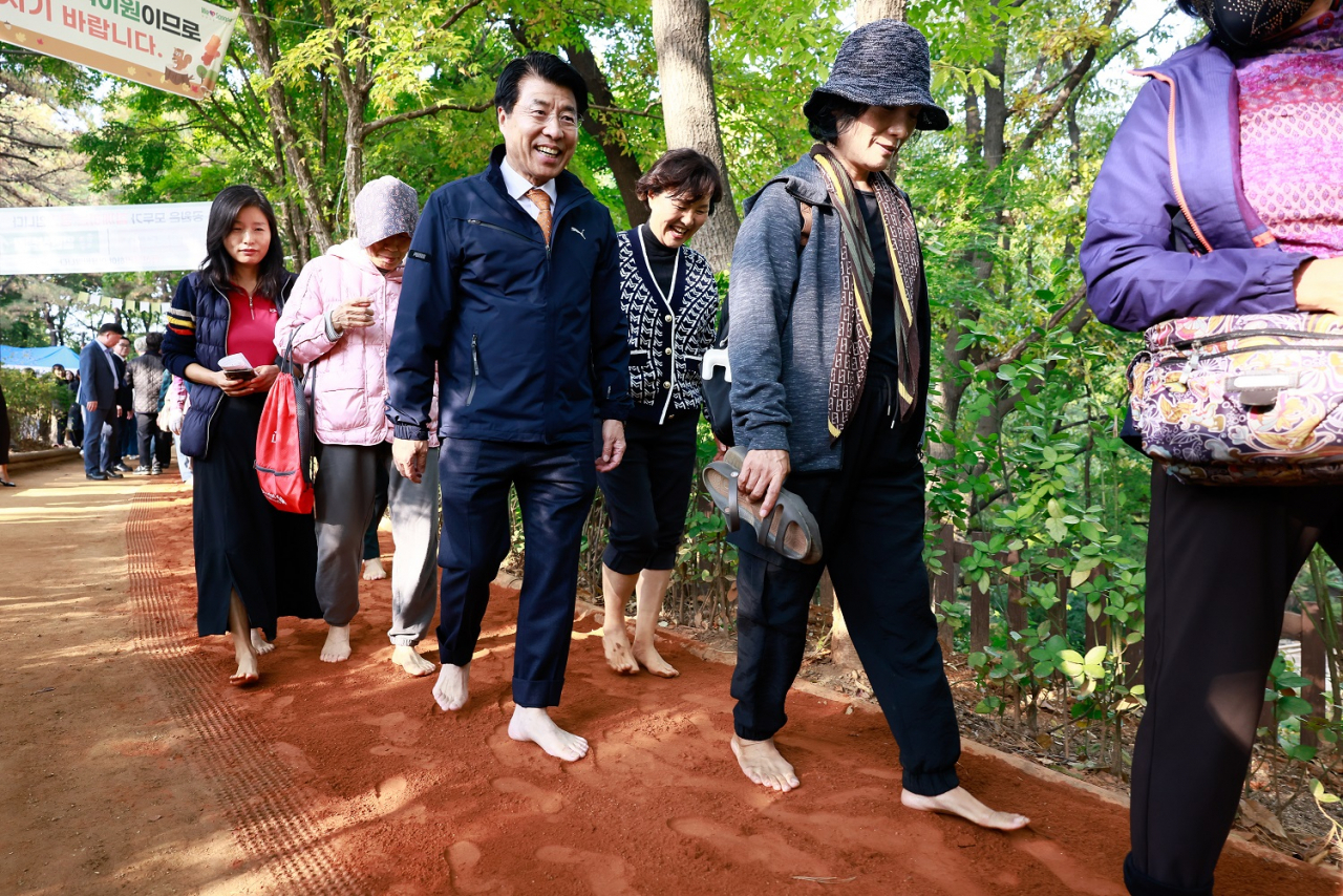 서울 송파구는 송파나루공원과 오금공원에 맨발로 걸을 수 있는 구민건강 황토체험존을 조성해 개장했다고 26일 밝혔다. 서강석 송파구청장이 맨발로 황톳길을 걷고 있다.[송파구 제공]