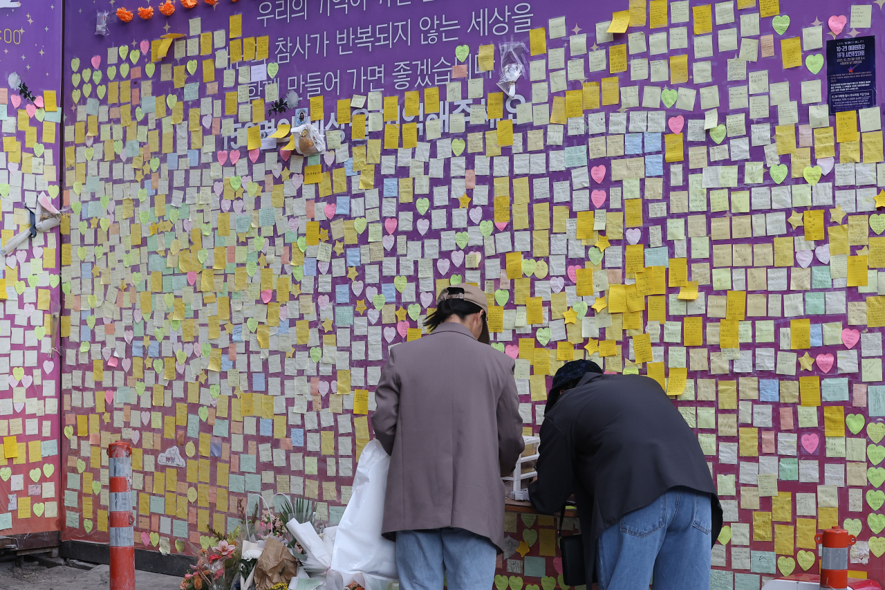 핼러윈 데이를 앞두고 시내 번화가에 인파 밀집이 예상되는 가운데 27일 서울 용산구 이태원 참사 추모 현장을 찾은 시민들이 추모 글귀를 적고 있다. [연합]