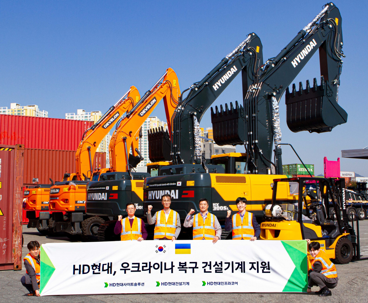 HD현대 임직원들이 29일 부산신항에서 우크라이나 기증 건설장비 5대를 선적하기 전 기념촬영을 하고 있다. [HD현대 제공]