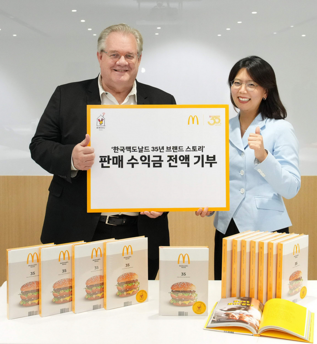 한국맥도날드가 창립 35주년을 기념해 출간한 사사(社史( ‘한국맥도날드 35년 브랜드 스토리’의 판매 수익금 전액을 한국RMHC에 기부했다. 제프리 존스(왼쪽) 한국RMHC 회장과 김기원 한국맥도날드 대표이사가 기념촬영을 하고 있다. [한국맥도날드 제공]