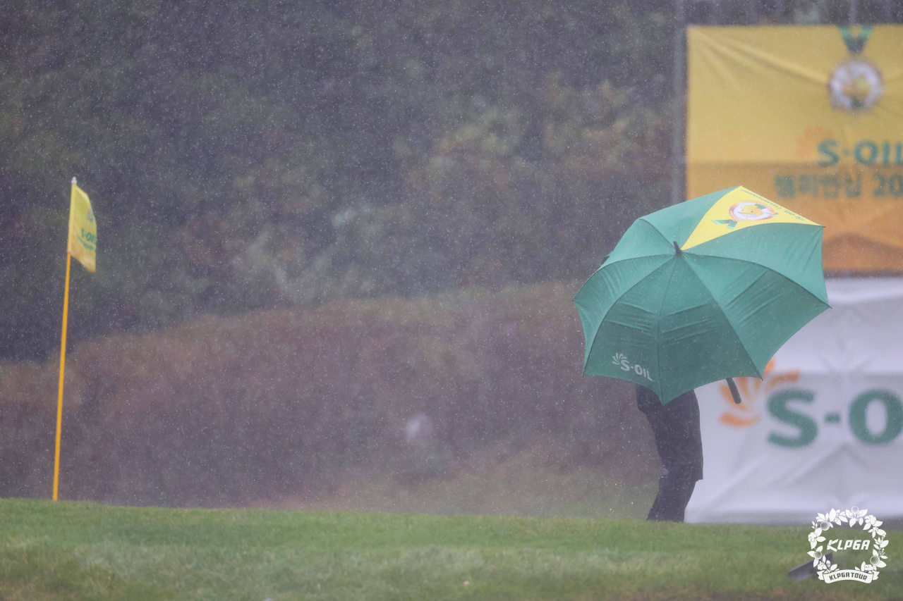 17번홀 그린 위로 비가 쏟아지고 선수가 우산을 쓴 채 이동하고 있다.[KLPGA 제공]