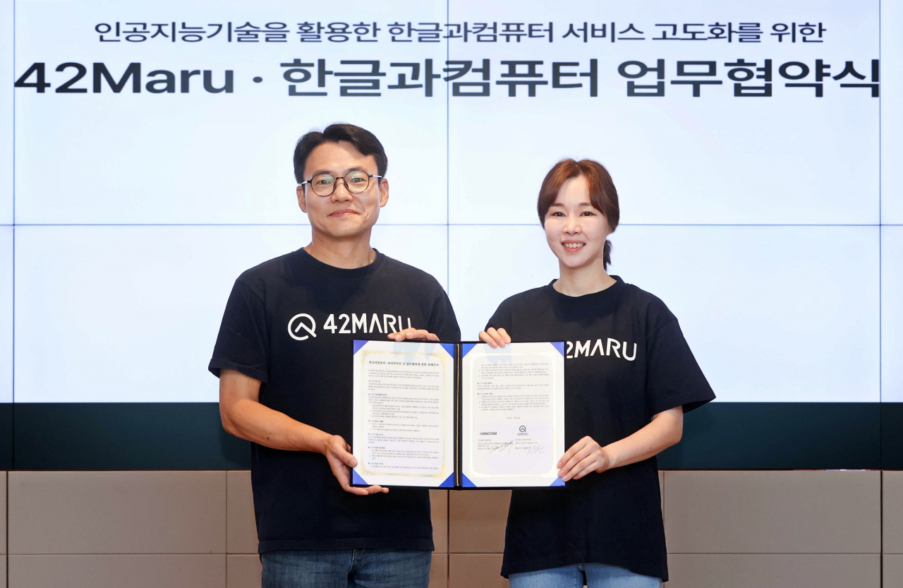 김연수(오른쪽) 한글과컴퓨터 대표와 김동환 포티투마루 대표가 전략적 파트너십을 맺는 계약서에 서명하고 포티투마루가 선물한 티셔츠를 입고 기념 촬영했다. [한글과컴퓨터 제공]