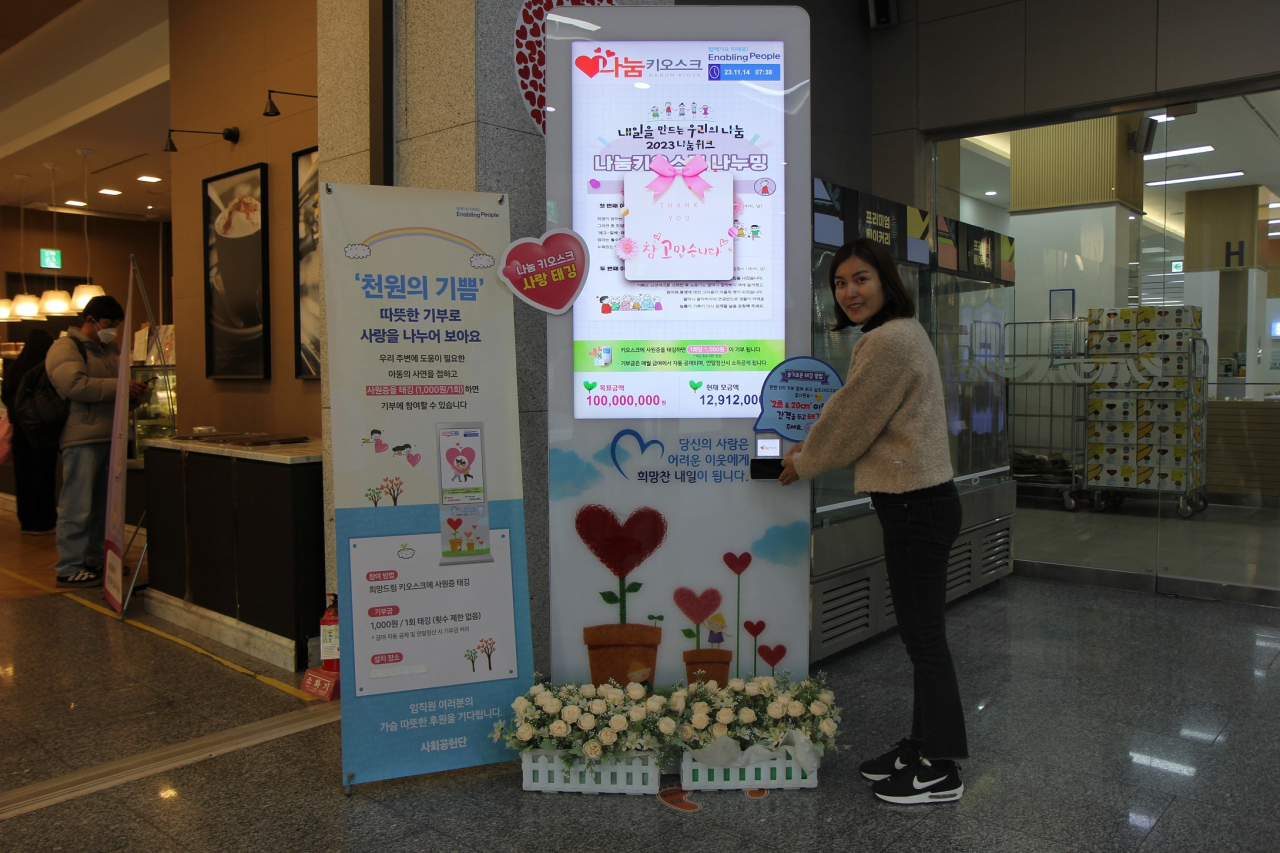 삼성전기 직원이 14일 경기 수원시 본사에서 나눔키오스크 기부에 참여한 뒤 인증 기념촬영하고 있다. [삼성전기 제공]