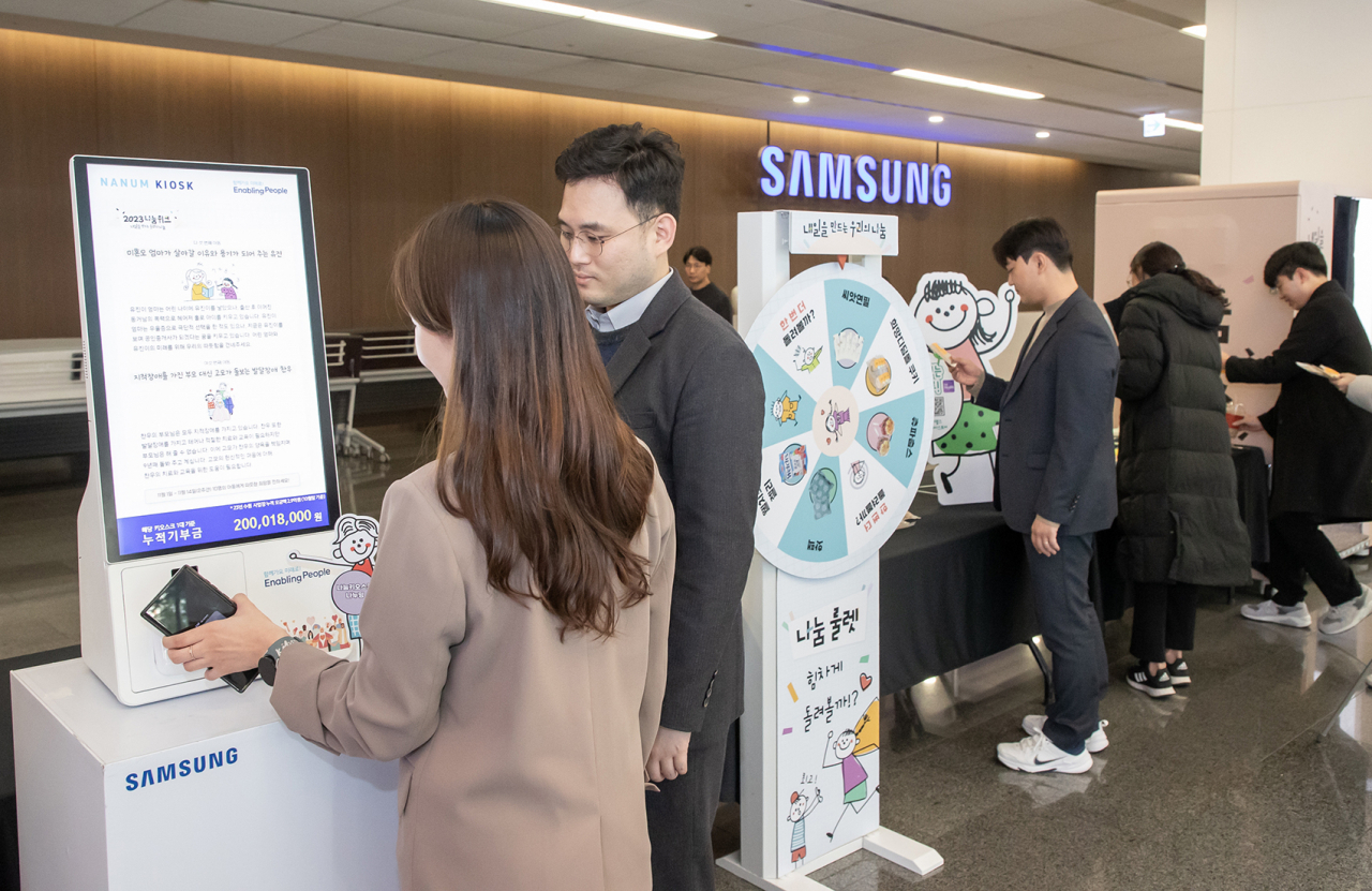 삼성전자 임직원들이 14일 '2023 하반기 삼성 나눔의 날' 행사가 열린 삼성전자 화성 부품연구동(DSR) 로비에 설치된 나눔키오스크에서 사원증을 태깅하며 '일상 속 기부'를 실천하고 있다. [삼성전자 제공]