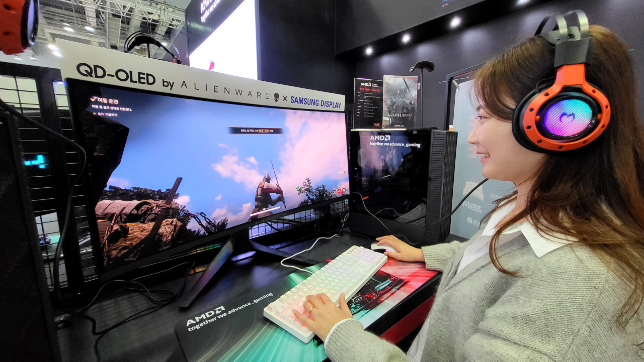 삼성디스플레이 모델이 지스타 2023 AMD 부스에 전시된 ‘에일리언웨어 34 커브드 QD-OLED 게이밍 모니터’로 대규모 이용자 간 대전 '워헤이븐'을 체험해보고 있다. [삼성디스플레이 제공]