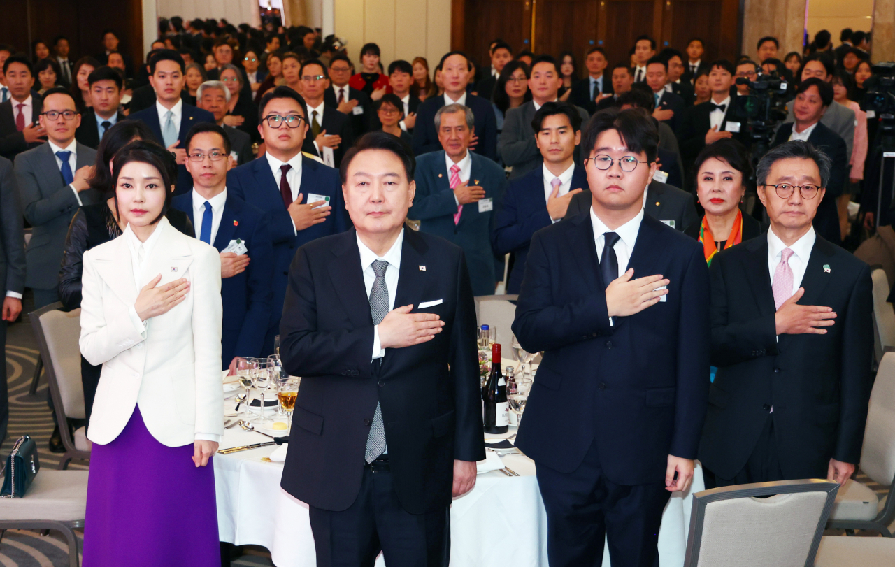 영국을 국빈 방문한 윤석열 대통령과 부인 김건희 여사가 20일(현지시간) 런던의 한 호텔에서 열린 동포 만찬 간담회에서 국기에 경례하고 있다. [연합]