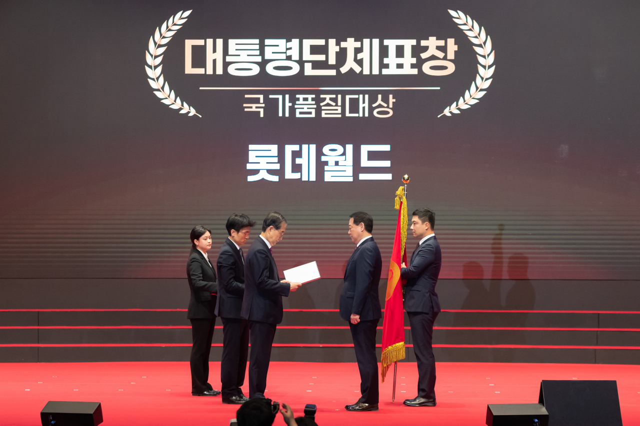 롯데월드의 최홍훈 대표가 한덕수 총리로부터 국가품질대상 대통령 표장을 받고 있다.