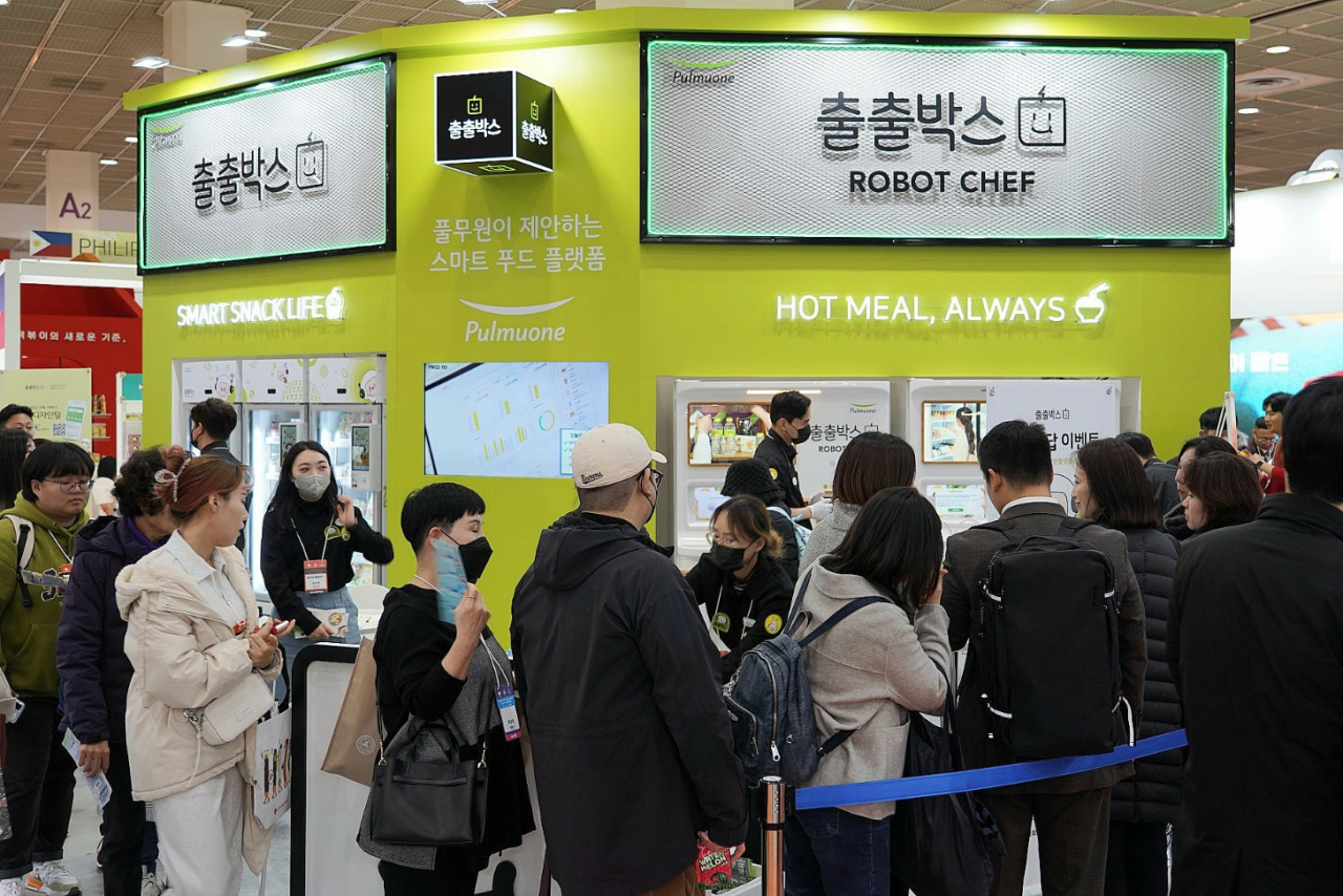 지난 23일 서울국제식품산업전을 찾은 방문객들이 ‘출출박스 로봇셰프’ 즉석조리 음식을 시식하기 위해 대기하고 있다. [풀무원 제공]
