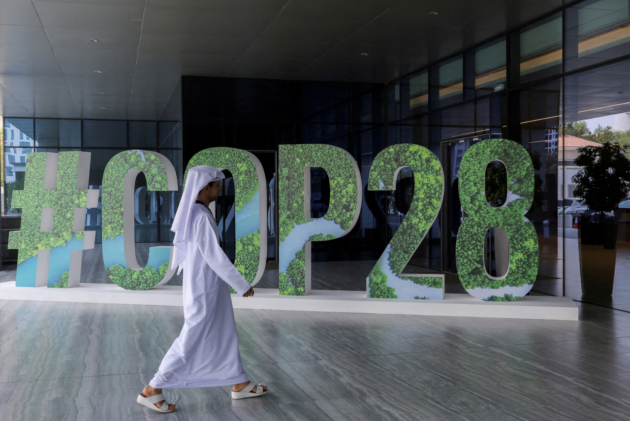아랍에미리트 아부다비에서 한 행인이 ‘COP28’ 개최를 알리는 전시물 앞을 지나고 있다. [로이터]